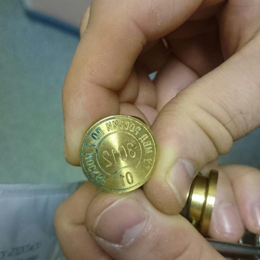 Металлическая печать с номером в руке